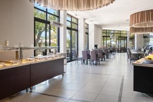 a dining room with tables and chairs and windows at Long Beach Hotel & Resort in Lóngos