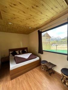 a bedroom with a bed and a large window at Kübes By The Raasta in Jispa