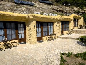 a stone building with windows and tables and chairs at Sirocave barlang apartmanok in Sirok