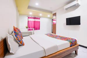 a bedroom with a bed and a tv on a wall at FabHotel Aarvi Inn in Aurangabad +23 photos