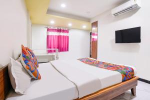a bedroom with a bed and a tv on a wall at FabHotel Aarvi Inn in Aurangabad