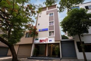 a tall white building with a sign on it at FabHotel Aarvi Inn in Aurangabad