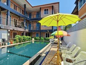 a pool with chairs and an umbrella next to a building at Ora House in San Kamphaeng