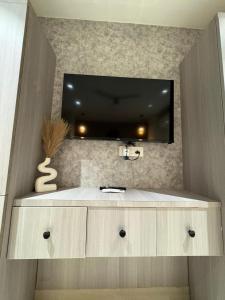 a bathroom with a sink and a tv on a wall at Jsrcozystays in Rājpur