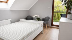 a bedroom with a bed and two chairs and a window at Dom uKromki z kominkiem i widokiem na Śnieżkę in Sosnówka