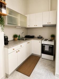 a white kitchen with white cabinets and a stove at Asana by Agora Flats in Thessaloniki