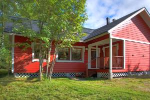 a red house with a tree in front of it at Talvitahko 3 in Nilsiä