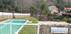 a swimming pool in a yard with a stone wall at Gerês maravilha in Geres