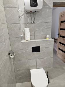 ein Badezimmer mit Toilette und einem Fernseher an der Wand in der Unterkunft Hostel 405 in Polanka Wielka