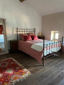 a bedroom with a bed with red pillows and a rug at Maison centre historique in Lectoure