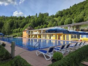 a large swimming pool with chairs and umbrellas at Ferienwohnung Bächle in Bad Peterstal