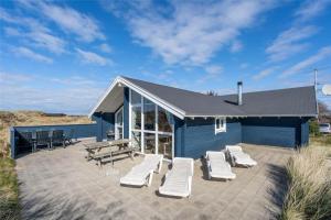 a blue building with white lounge chairs and a table at 555-Hvide-Sande-Tornbjerrevej-32 in Havrvig