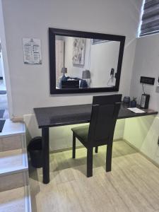 a black desk with a chair and a mirror at Athlone Lodge in Pietermaritzburg
