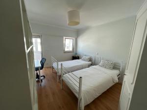 a room with two beds and a desk in it at Sal Guest House in Costa da Caparica