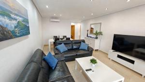 a living room with a leather couch and a flat screen tv at Benidorm Ambra in Villajoyosa