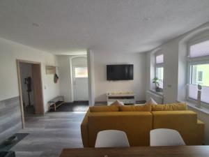 a living room with a couch and a tv at FeWo Herzenstölen in Sebnitz