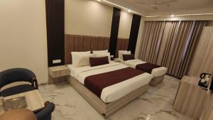a hotel room with two beds and a chair at Hotel The Best IGI Delhi in Kānpur