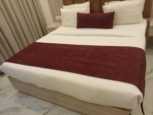 a bed with white and red sheets and pillows at Hotel The Best IGI Delhi in Kānpur