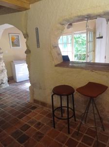 two stools in a room with a stone wall at Gîte rustique en Morvan in Brassy