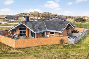 a house with a brick wall in a field at 461-Hvide-Sande-Tingodden-152 in Hvide Sande
