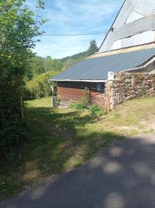 a building with a stone wall next to a house at Gîte rustique en Morvan in Brassy