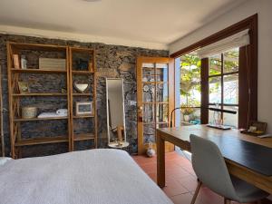 a bedroom with a table and a stone wall at Casa das Flores Funchal in Funchal
