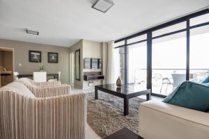 a living room with two couches and a table at Aquarius Luxury Suites in Bloubergstrand