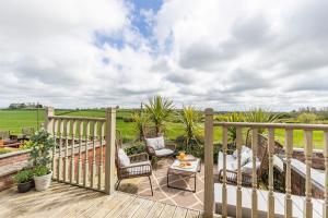 a wooden deck with two chairs and a table at 2BR House By Cozy Quarters Property Management Holiday Lets Sedgefield With Open Field & Countryside Views in Sedgefield