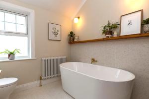 a white bath tub in a bathroom with a window at 2BR House By Cozy Quarters Property Management Holiday Lets Sedgefield With Open Field & Countryside Views in Sedgefield