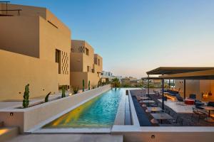 a swimming pool with tables and chairs next to a building at Enorme EOS Santorini - Adults Only in Pyrgos