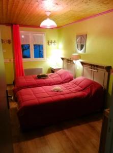 two beds in a room with red sheets at Gîte Le Chemin du Cap in Plévenon
