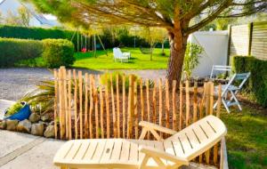 two wooden chairs and a fence with a tree at Gîte Le Chemin du Cap in Plévenon