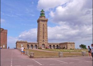 a brick building with a tower with a green top at Gîte Le Chemin du Cap in Plévenon