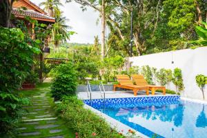a pool with two benches next to a house at Mango Village in Phú Quốc