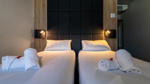 two beds in a room with towels on them at Hôtel Le Cyrano Bergerac in Bergerac
