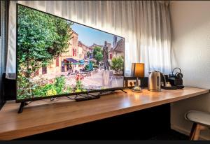 a large flat screen tv sitting on top of a desk at Hôtel Le Cyrano Bergerac in Bergerac