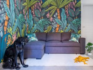 a black dog sitting in a living room with a couch at Tropical Boutique Apartment in Gallipoli