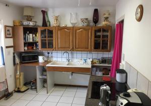 a kitchen with wooden cabinets and a sink at Brise Fraîche de la Montagne-Piscine et Jacuzzi-Appartement Cottage au rez-de-chaussée in Le Poujol-sur-Orb