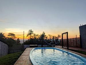 a swimming pool with a seesaw in front of a sunset at Casa com piscina, aconchegante, aceita pet in Cotia