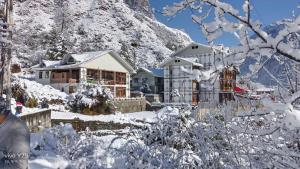 a house covered in snow in front of a mountain at Valmere Bayul Shangri-La Resort in Lachung