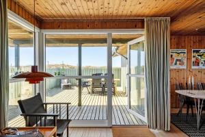 a living room with a deck with a table and chairs at 5514-Hvide-Sande-Riskrogvej-18-C in Havrvig +27 photos