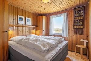 a bedroom with a large bed in a wooden wall at 5514-Hvide-Sande-Riskrogvej-18-C in Havrvig