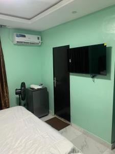 a bedroom with a bed and a television on the wall at Torax Lodge in Ibadan