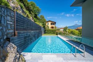 an infinity pool in a house with a stone wall at Condominio Modern House in Menaggio