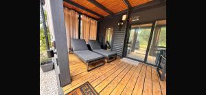 a porch with a black couch on a wooden deck at House no 4 in Pakoštane +19 photos