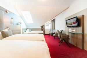 ein Hotelzimmer mit zwei Betten und einem Flachbildfernseher in der Unterkunft Hotel Hennies in Isernhagen
