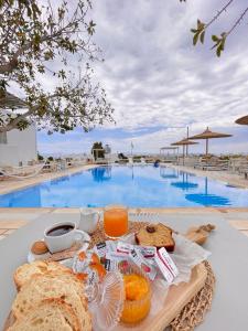 a breakfast tray with bread and orange juice next to a pool at Margarita Studios Ambelas in Ambelas
