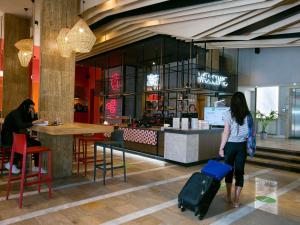 a woman with a suitcase in front of a restaurant at ibis Styles Dunarea Galati in Galaţi