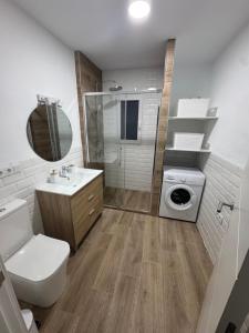 a bathroom with a toilet sink and a washing machine at Apartamentos Canoa centro y playa in Sanlúcar de Barrameda