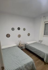 two beds in a room with white walls at Apartamentos Canoa centro y playa in Sanlúcar de Barrameda
